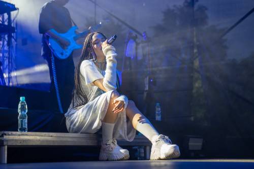 Sara James siedzi na scenie. W tle gitarzysta,