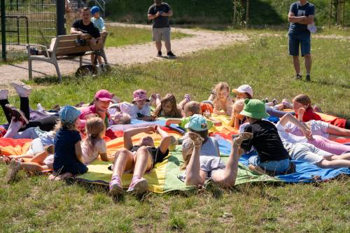 Dzieci podczas zabawy siedzą na chuście animacyjnej.