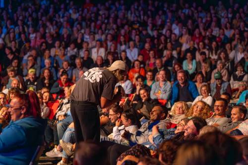 Michał Kempa z publicznością podczas Wieczoru Stand-up w ramach cyklu faktoria Kultury w Pruszczu Gdańskim. Michał nachyla się w stronę publiczności, zbliżenie.