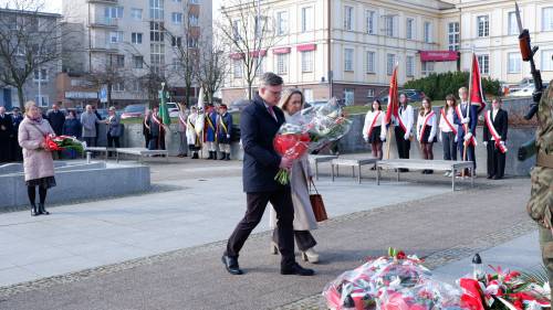 Goście składają kwiaty pod pomnikiem Nike. Z kwiatami przedstawiciele szkół.