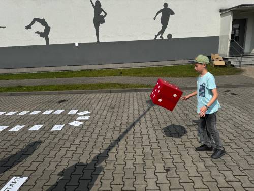 Uczestnik gry terenowej Środowisko ponad wszystko rzucający wielką kostką do gry.