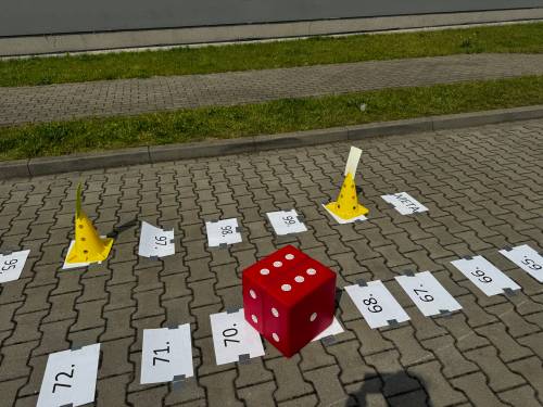 Pola planszy do gry i wielka kostka do gry w trakcie rzutu.