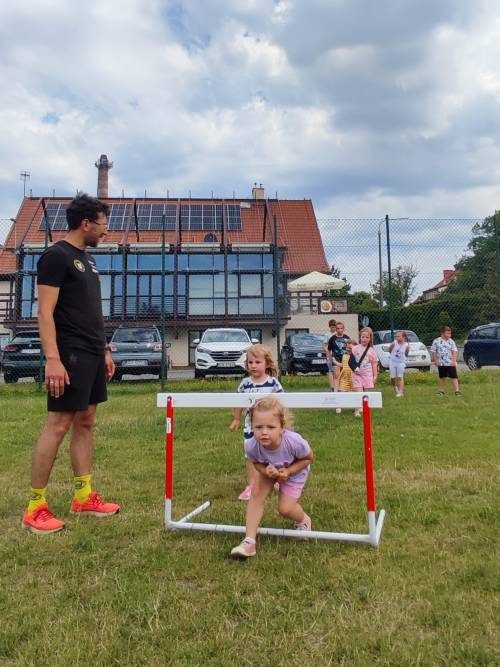 Zabawy ruchowe dzieci na świeżym powietrzu, dziewczynka biegnie pod bramką