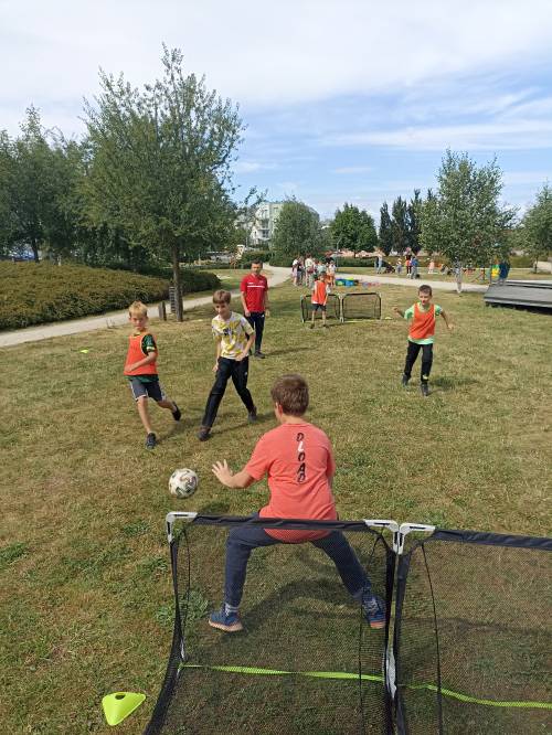 Chłopcy grają w piłkę nożną pod okiem trenera