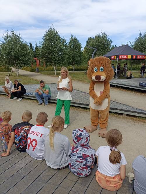 Pani z sanepidu rozmawia z dziećmi o różnych zagrożeniach, obok stoi lew Pruszek