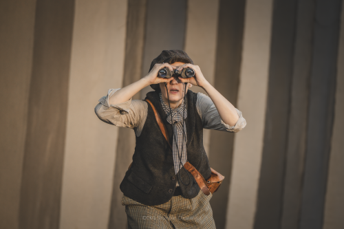 Spektakl dla dzieci pt. Szelmostwa Lisa Witalisa. Na zdjęciu aktor patrzący przez lornetkę