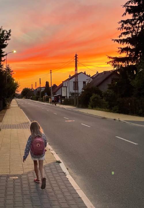 Dziewczyna z plecakiem idzie chodnikiem.