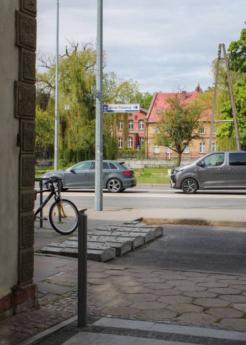 Widok na ulicę z autami zza rogu budynku.