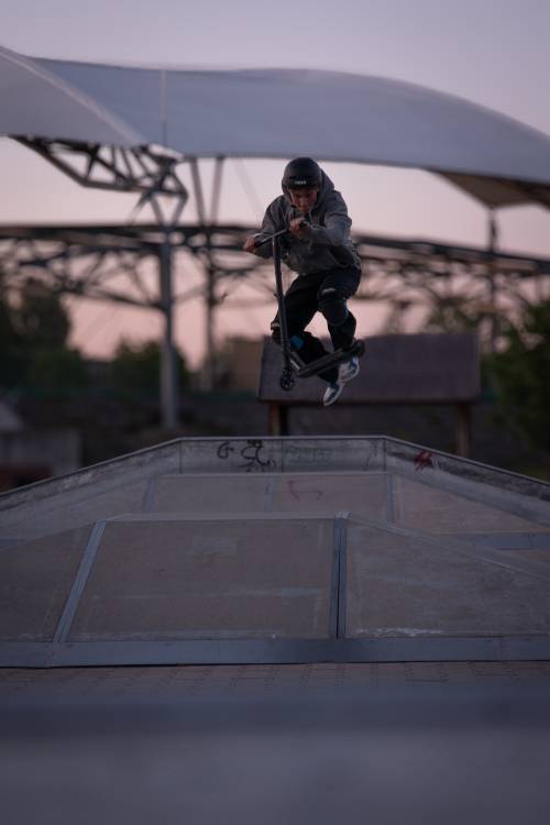 Skatepark - nastolatek robi ewolucje na hulajnodze.