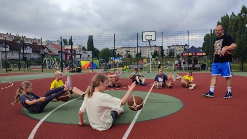 Wakacje w mieście - dzieci wykonują ćwiczenia z piłką do koszykówki