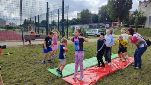 Dzieci stoją na matach i wykonują ćwiczenia na świeżym powietrzu