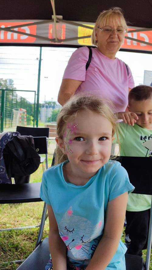 Na zdjęciu na pierwszym planie dziewczynka z namalowanymi kwiatkami na buzi