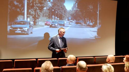 Burmistrz przed ekranem na sali kinowej.