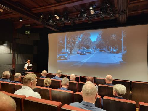 Widok na ekran zza pleców osób siedzących na sali kinowej.