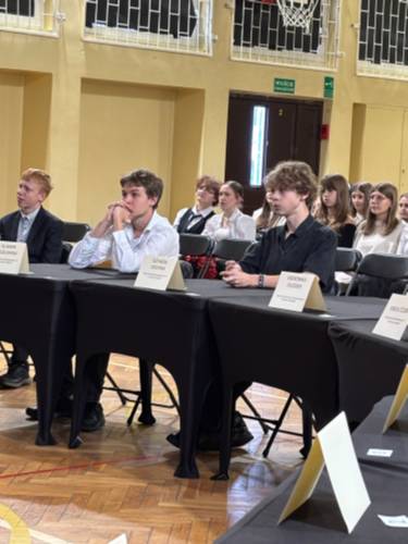 Grupa nastoletnich uczniów siedzących przy stołach